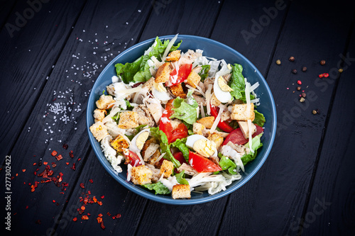 View from above Caesar salad with chicken, lettuce, parmesan cheese, tomato. Copy space for design. Healthy food bowl. Dieting. bowl on dark wooden background. healthy and balanced food