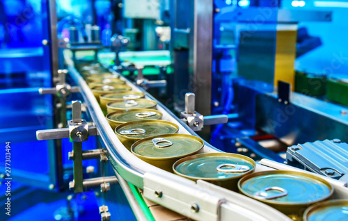 Canned food products on conveyor belt in distribution warehouse.parcels transportation system concept. photo