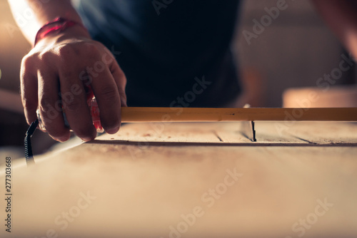 Handsome man carpenter taking measurements of some wood,repair, building and home concept - close up of male hands measuring wood flooring