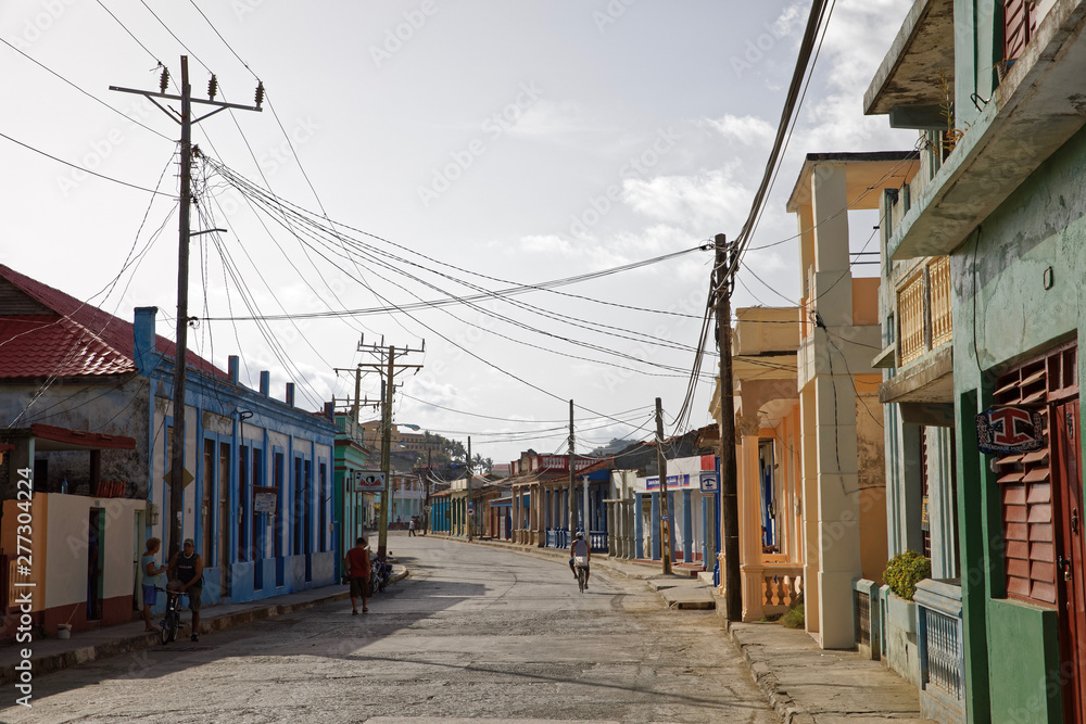 Baracoa, Cuba - July 14, 2018: Classic cuban backstreet with bike and rickshaw Baracoa, Cuba - July 14, 2018: Classic cuban backstreet with bike and rickshaw