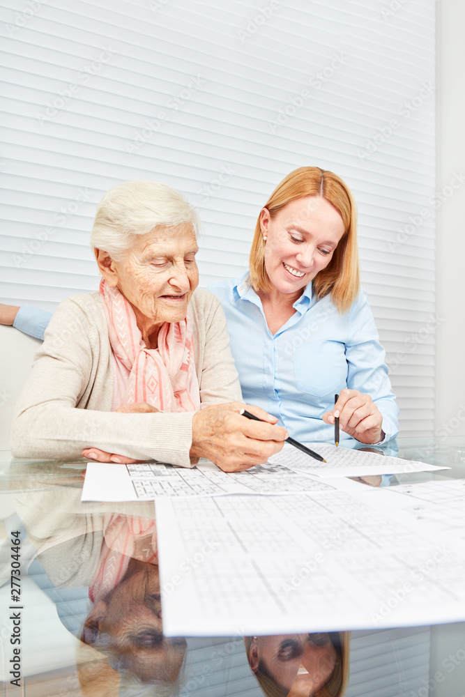 Young woman solves puzzles together with elderly woman Young woman solves puzzles together with elderly woman