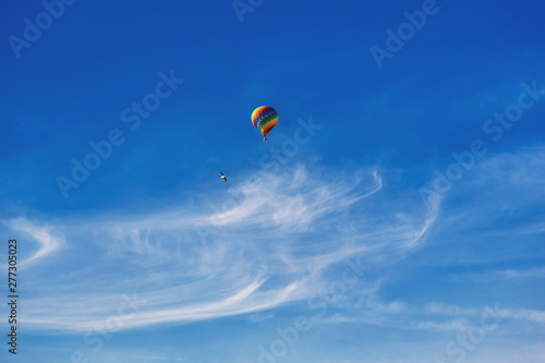 Balloon flying through the blue sky among the clouds. Freedom, adventure, loneliness. Birds are stolen around