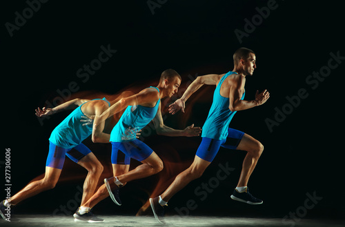 Professional male runner training isolated on black studio background in mixed light. Man in sportsuit practicing in run or jogging. Healthy lifestyle  sport  workout  motion and action concept.