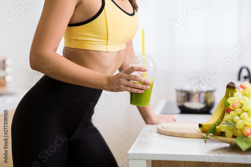 Fit girl holding detox smoothie, restoring energy