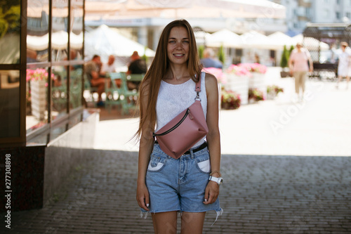 Beautiful slim girl looking at the camera and smiling. Portrait of a girl on the street.