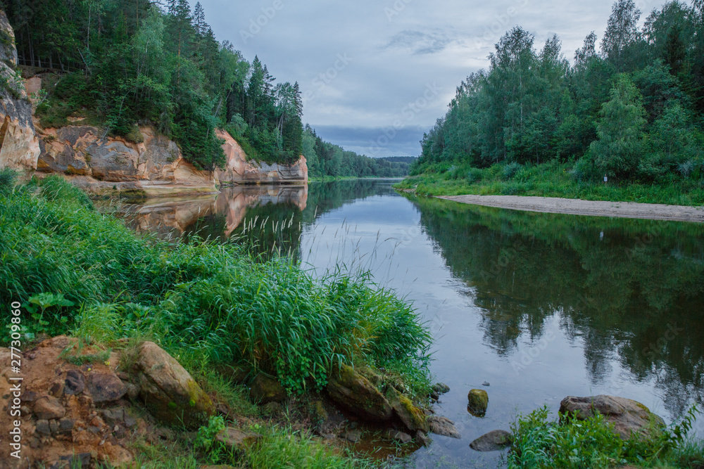 Fototapeta premium City Cesis, Latvia Republic. Red rocks and river Gauja. Nature and green trees in summer. July 4. 2019 Travel photo.