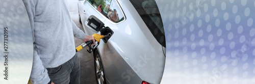 Man holding fuel pump nozzle and refilling car; panoramic banner