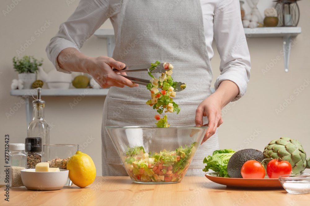 Cooking. The chef is pissed, in the process of a vegetarian salad in the home kitchen. Light background. Restaurant menu, menu, recipe book. Healthy nutrition, detox Cooking. The chef is pissed, in the process of a vegetarian salad in the home kitchen. Light background. Restaurant menu, menu, recipe book. Healthy nutrition, detox