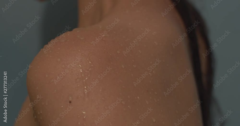 Water drops on woman’s shoulder 4k close up. Drops of water fall and run down the wet tanned naked body of young girl macro skin shooting bathing showering skincare beauty treatment on blue background Water drops on woman’s shoulder 4k close up. Drops of water fall and run down the wet tanned naked body of young girl macro skin shooting bathing showering skincare beauty treatment on blue background