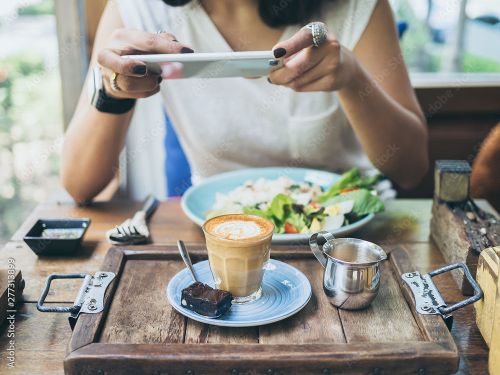 Woman's hands taking photo of coffee cup on wooden table by smartphone Woman's hands taking photo of coffee cup on wooden table by smartphone