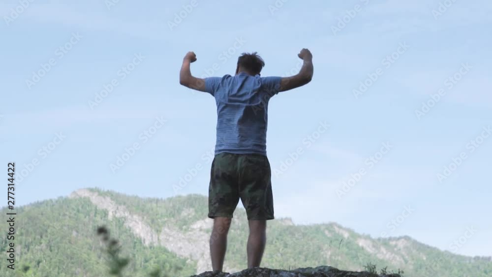 Man raises hands up standing back on mountain top morning sun shine slow motion. No face male silhouette figure in sportswear enjoy life wanderlust world. Man raises hands up standing back on mountain top morning sun shine slow motion. No face male silhouette figure in sportswear enjoy life wanderlust world.