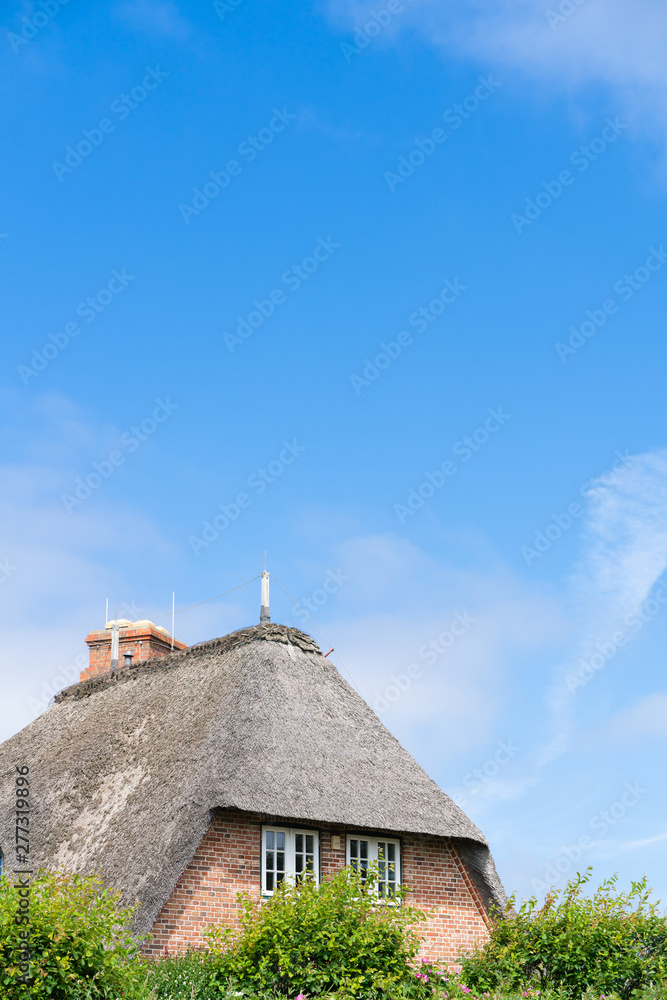Typical house with straw roof in small village on Sylt island, Germany. Typical house with straw roof in small village on Sylt island, Germany.