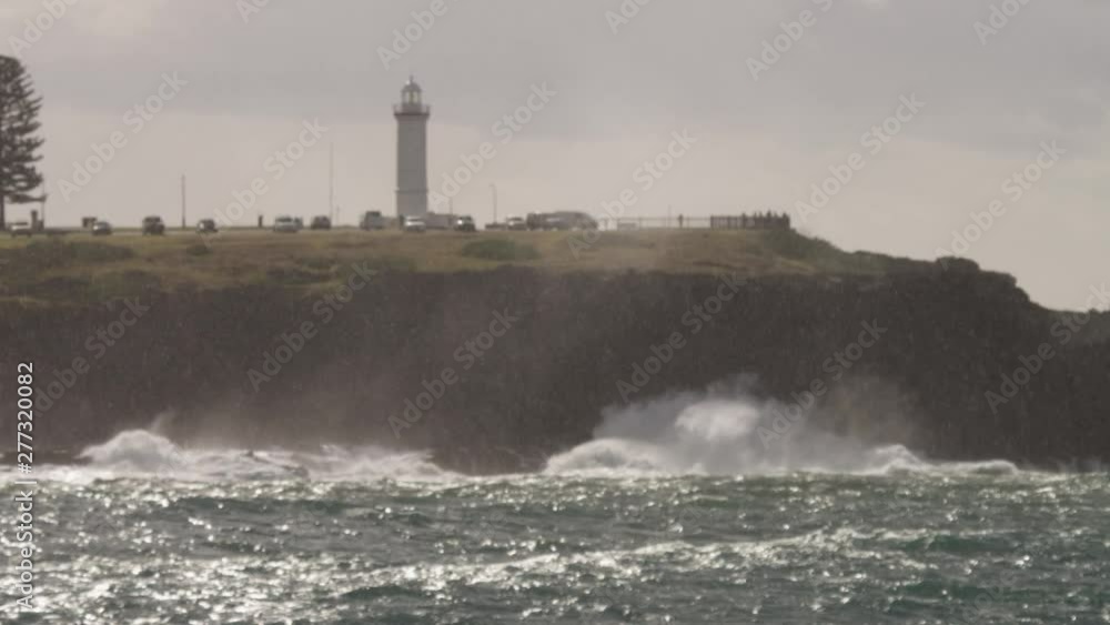 Pull focus through rain of waves breaking onto the rocks at the foot of a lighthouse. Slow Motion. Pull focus through rain of waves breaking onto the rocks at the foot of a lighthouse. Slow Motion.