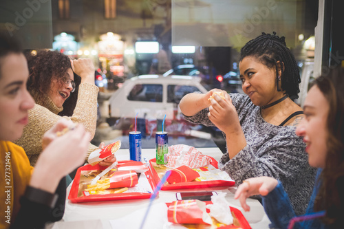 group of girlfriends eating hotdog in fast food