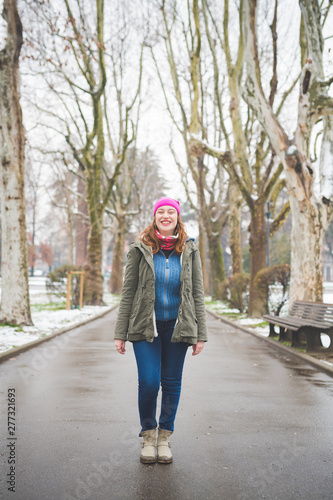 young happy woman standing in tree lined avenue and smiling