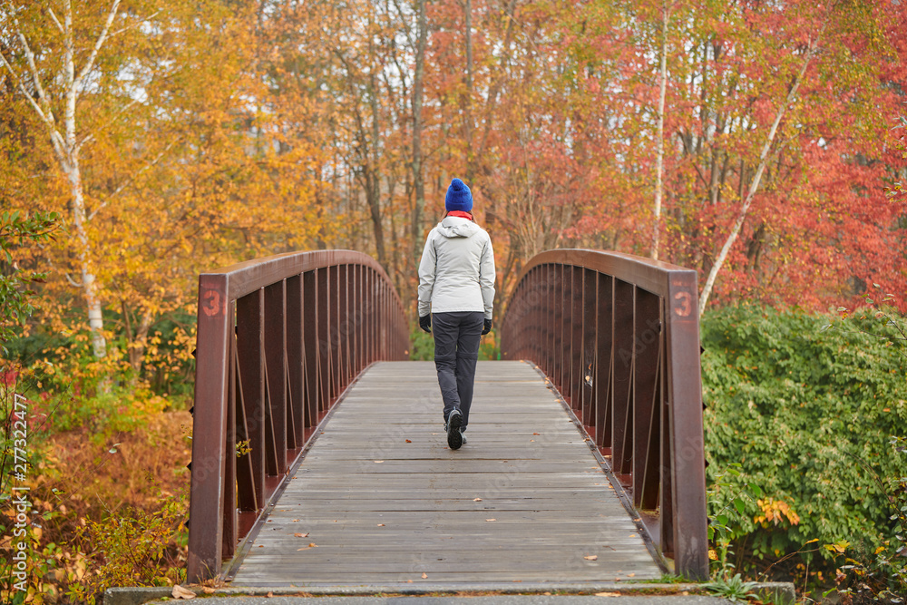 Woman hiking at Stowe Recreation Path on autumn day in Vermont, USA.