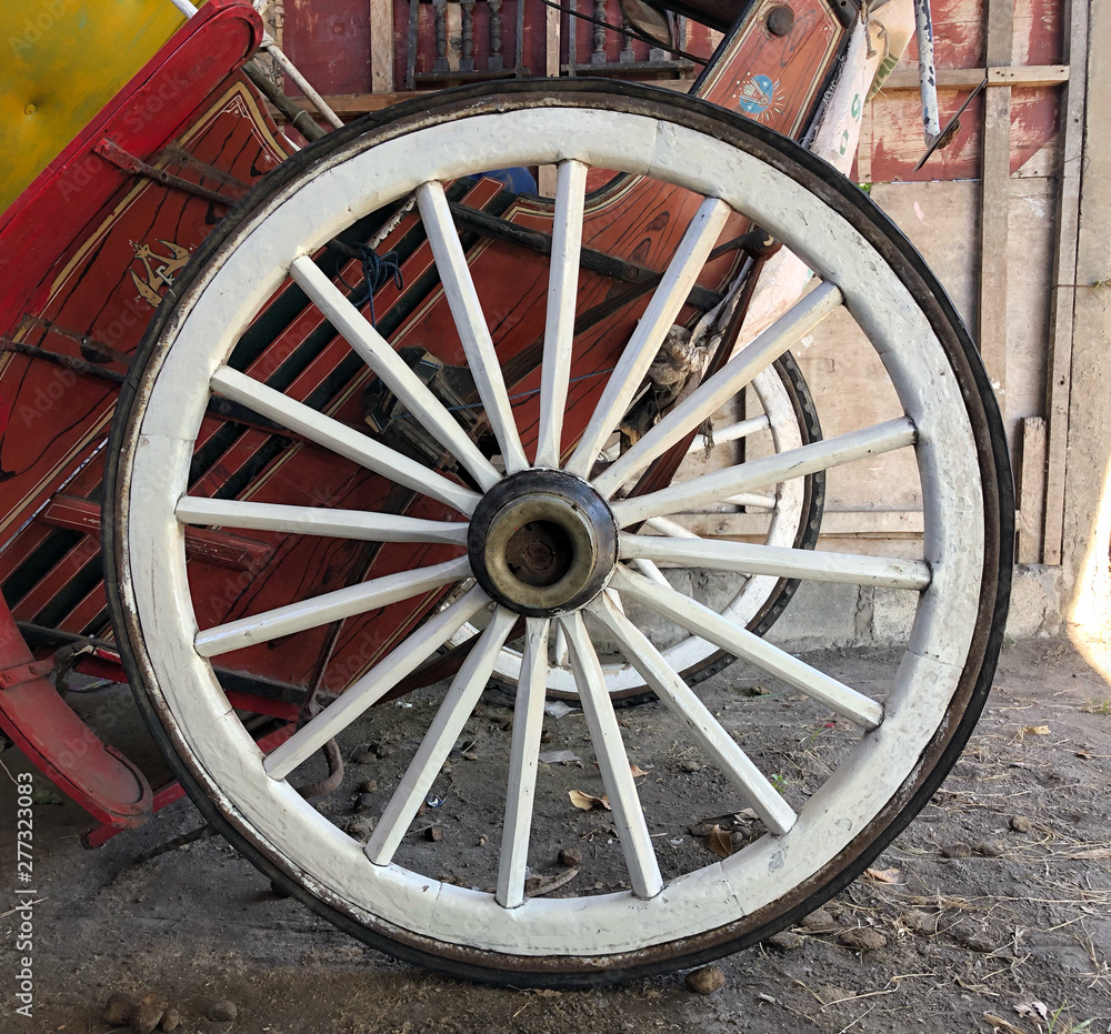 Old ironed, white  wagon or carriage wheel on street