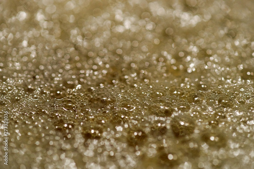 A macro - shallow depth of field - image of the bubbling surface of simmering ghee; having just changed from melted butter, into clarified butter.