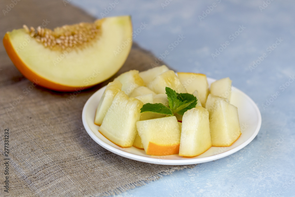 Ripe fresh yellow melon cut into pieces on a blue background. Ripe fresh yellow melon cut into pieces on a blue background.