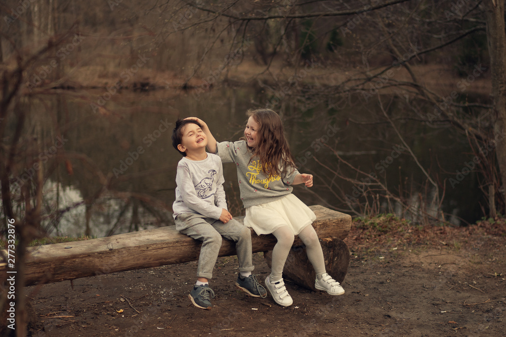 smiling girl touching boy's hair sitting on the wooden bench