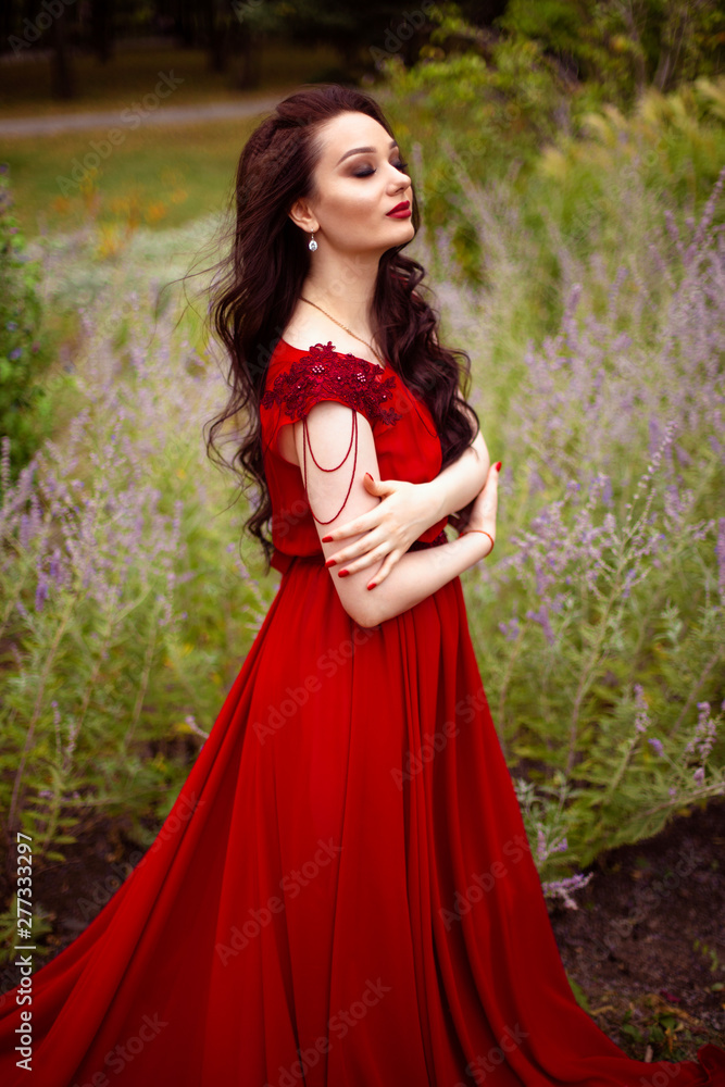 Portrait of a young brunette woman in a red dress with a train Portrait of a young brunette woman in a red dress with a train