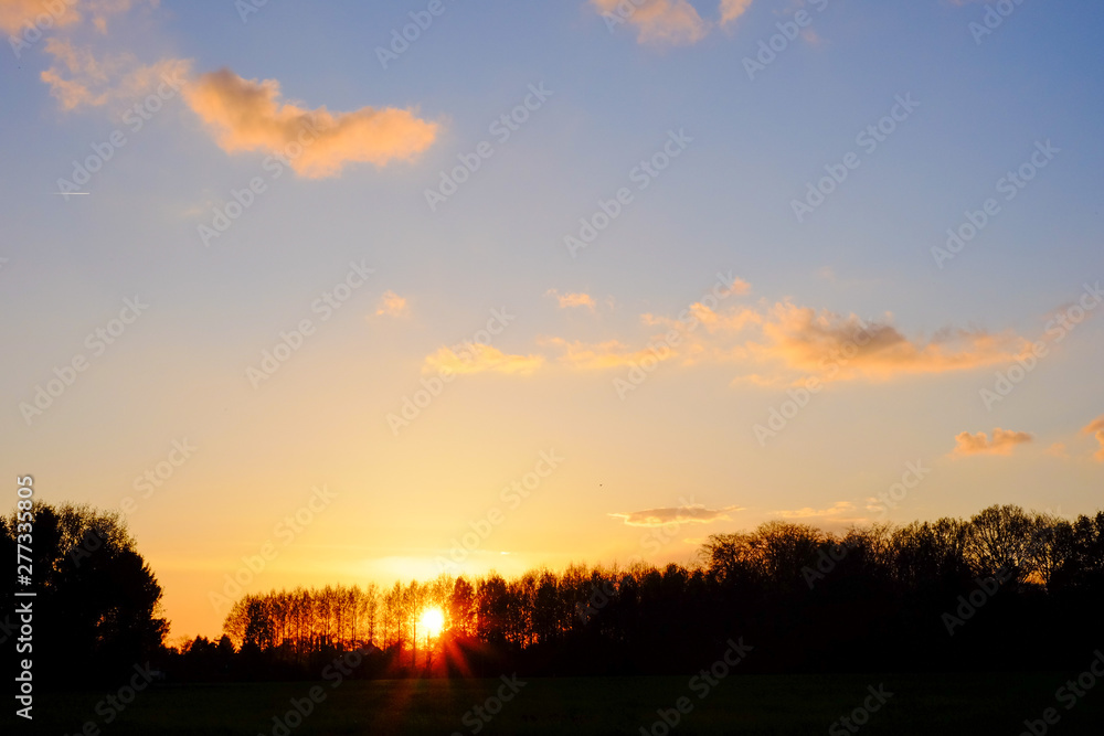 Natural Sunset or Sunrise Over Field Or Meadow with a Bright Dramatic scenic and colorful Sky against a Dark Ground.