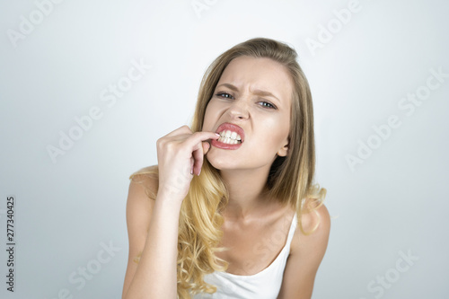 blond young woman suffering tooth pain showing her teeth with finger close up isolated white background