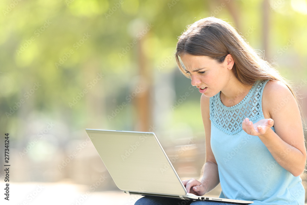 Confused woman using a laptop in a park Confused woman using a laptop in a park