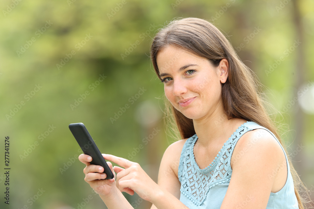 Smiley woman holding smart phone looking at you on green