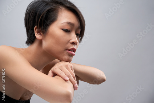 Portrait of Asian young fashion model with short black hair posing at camera isolated on grey background