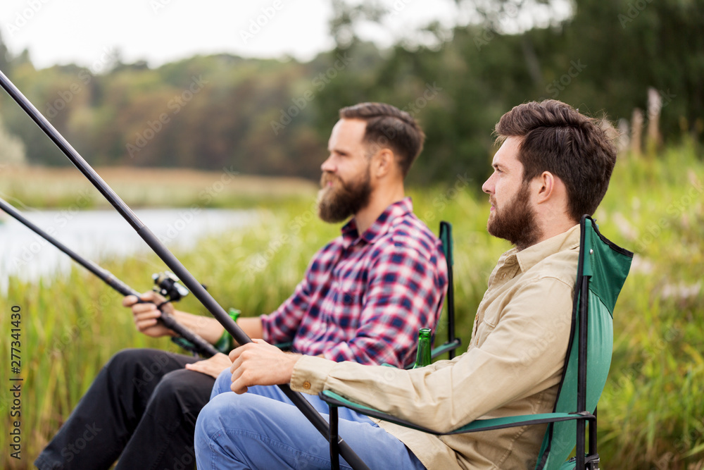 leisure and people concept - male friends with fishing rods on lake leisure and people concept - male friends with fishing rods on lake