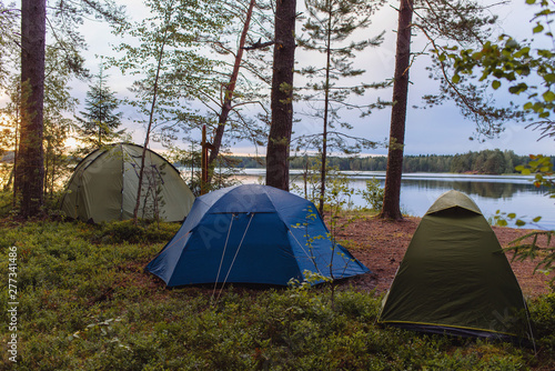 Adventures camping tourism and tent under the view forest landscape near water outdoor in summer evening and sunset sky. Camping and travel concept. 