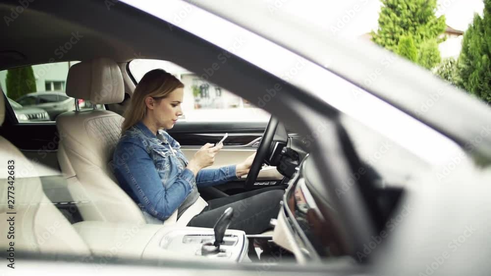 Young woman sitting in car, using smartphone. Slow motion. Young woman sitting in car, using smartphone. Slow motion.