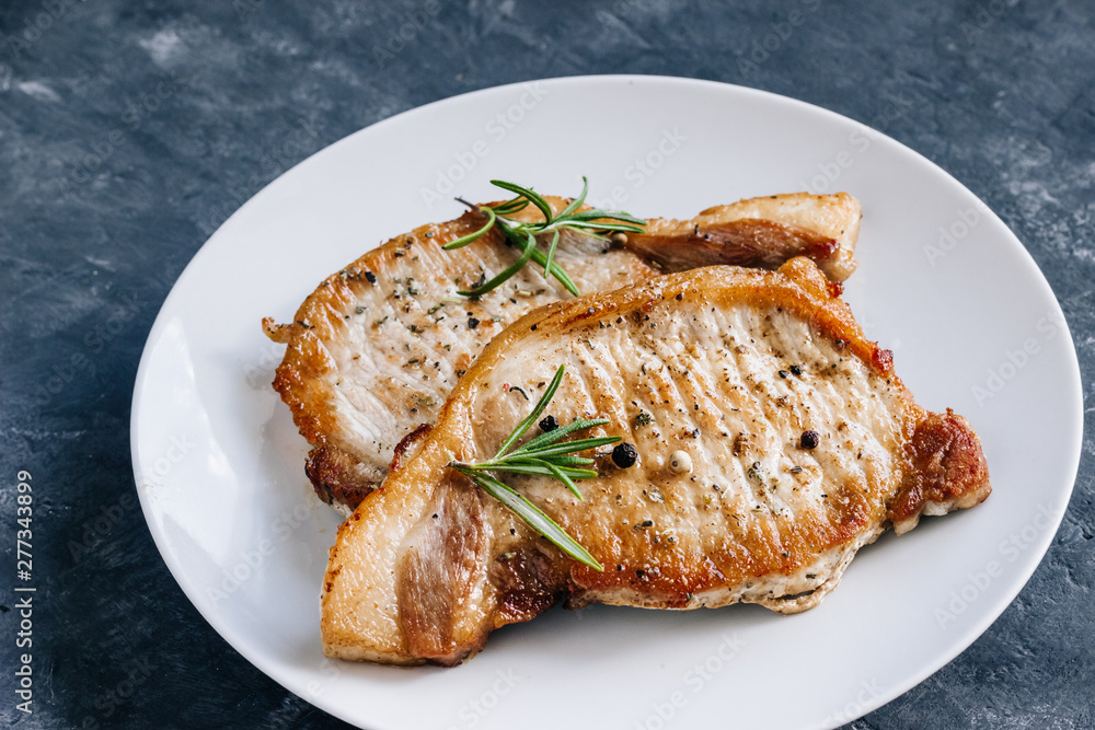 Roasted pork steaks in a plate with Rosemary.