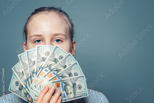 Rich girl holding money cash US dollars on blue background photo