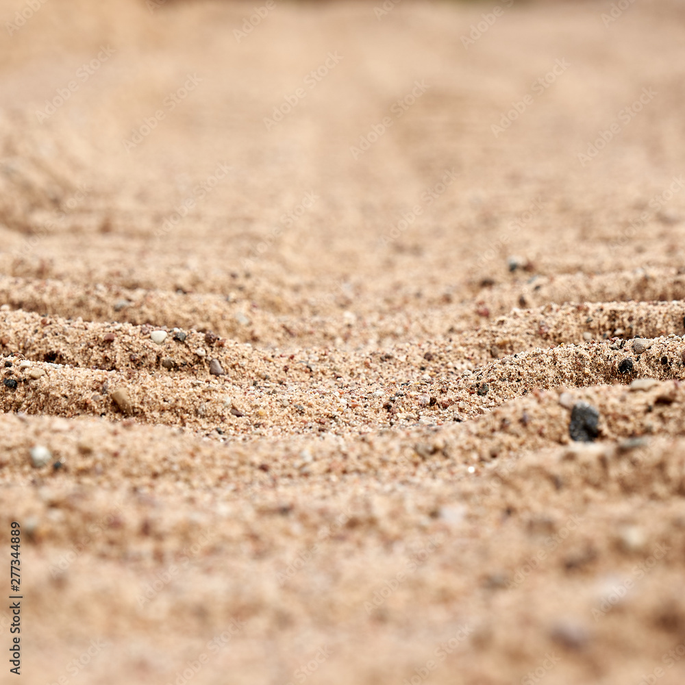 Background tire tracks of cars on the sand closeup. Part of the background is blurred. Background tire tracks of cars on the sand closeup. Part of the background is blurred.