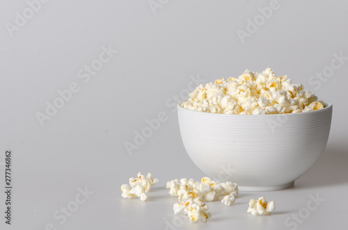 popcorn in a bowl isolated on white with few popcorn beside bowl