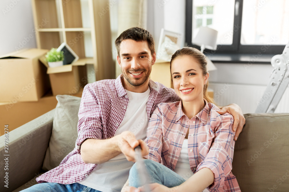 mortgage, people and real estate concept - happy couple moving to new home and taking picture by selfie stick mortgage, people and real estate concept - happy couple moving to new home and taking picture by selfie stick
