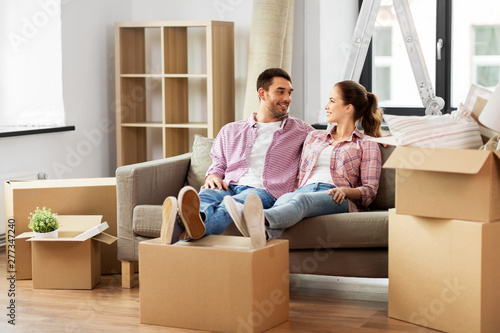 moving, people, repair and real estate concept - happy couple with cardboard boxes sitting on sofa at new home © Syda Productions