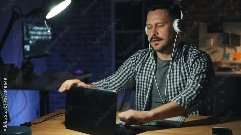 Tired office worker beardedmiddle-aged man is turning off lamp and laptop and leaving workplace at night going away from dark room. People and career concept. Tired office worker beardedmiddle-aged man is turning off lamp and laptop and leaving workplace at night going away from dark room. People and career concept.