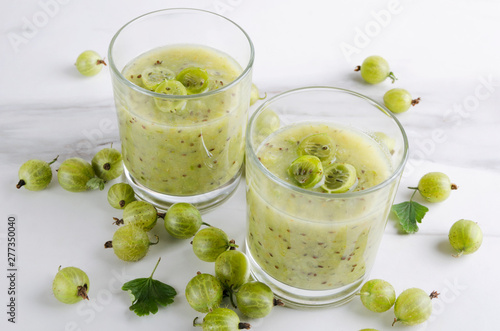 Closeup of two glasses of organic sweet smoothie, gooseberries on the white table