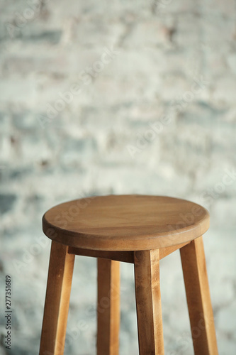 Round wooden stool with brick wall background