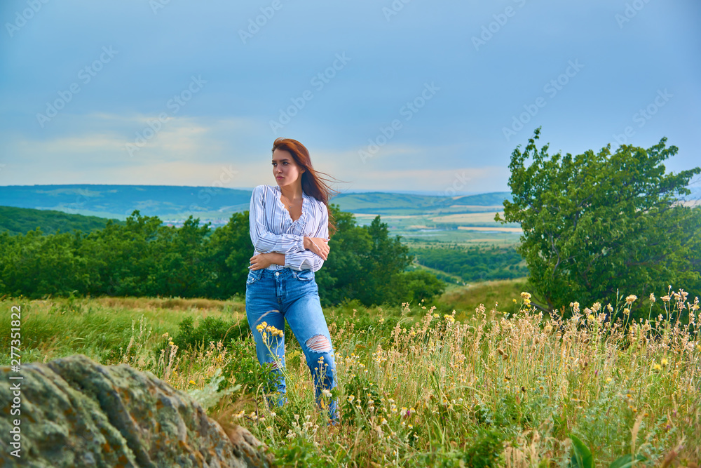 Girl in white dress standing back on the top of Caucasus mountain with a scenery view to sunset at green valley. Female travel nature concept.