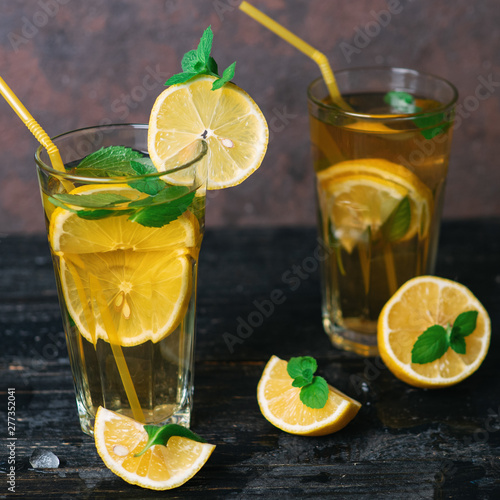 Summer refreshing lemonade with lemon and mint on a wooden table close-up