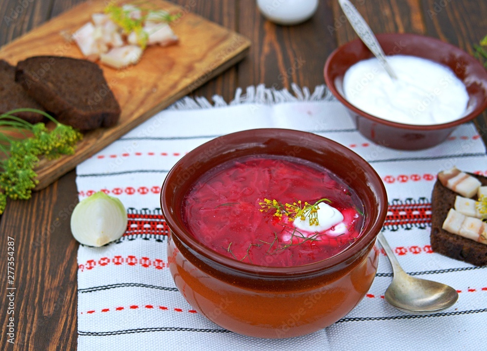 Borscht, hot soup with beets, cabbage and carrots in a clay bowl. Served with sour cream, rye bread and bacon. Borscht, hot soup with beets, cabbage and carrots in a clay bowl. Served with sour cream, rye bread and bacon.