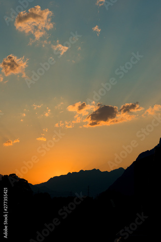 golden orange sunset with mountain silhouette and fading blue sky