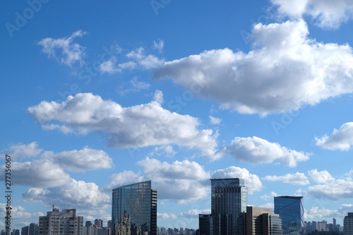 Flat cityscape with blue sky, white clouds and sun. Modern city skyline flat panoramic background. Urban city tower skyline illustration © lightscience
