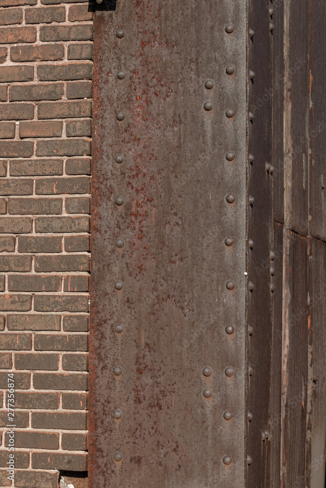 Riveted steel corner with heavy rust patina, brown brick, copy space, vertical aspect Riveted steel corner with heavy rust patina, brown brick, copy space, vertical aspect