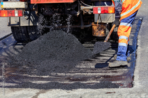 Obraz na plátne Road service worker rasbrasyvaet part of the asphalt with a shovel for patching