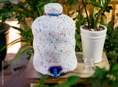 30 liter bottle of water covered by cover made from plastic bag 